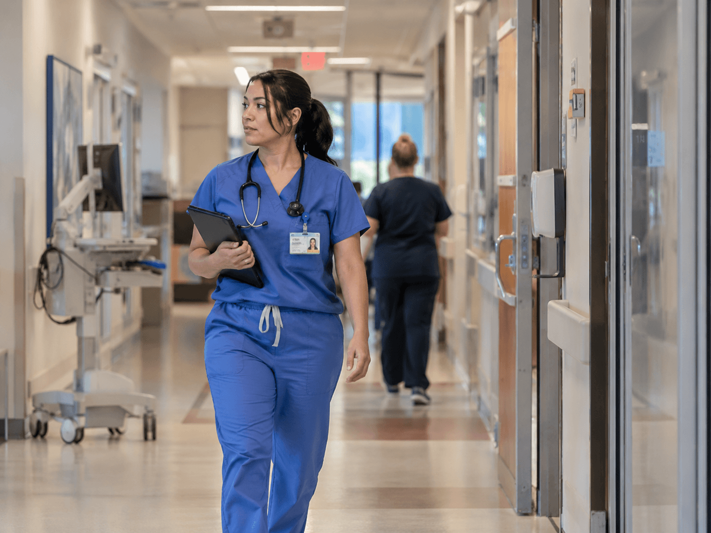 A credentialed clinician moving through a hospital corridor — the end point of a credentialing file that cleared committee on time.